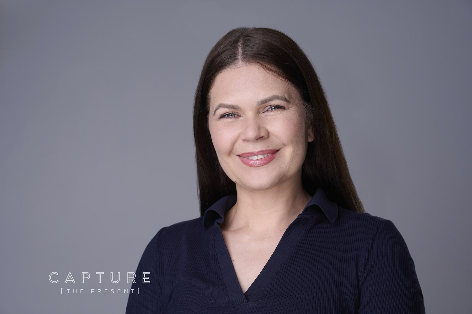 Team member with dark hair photographed on a soft grey backdrop