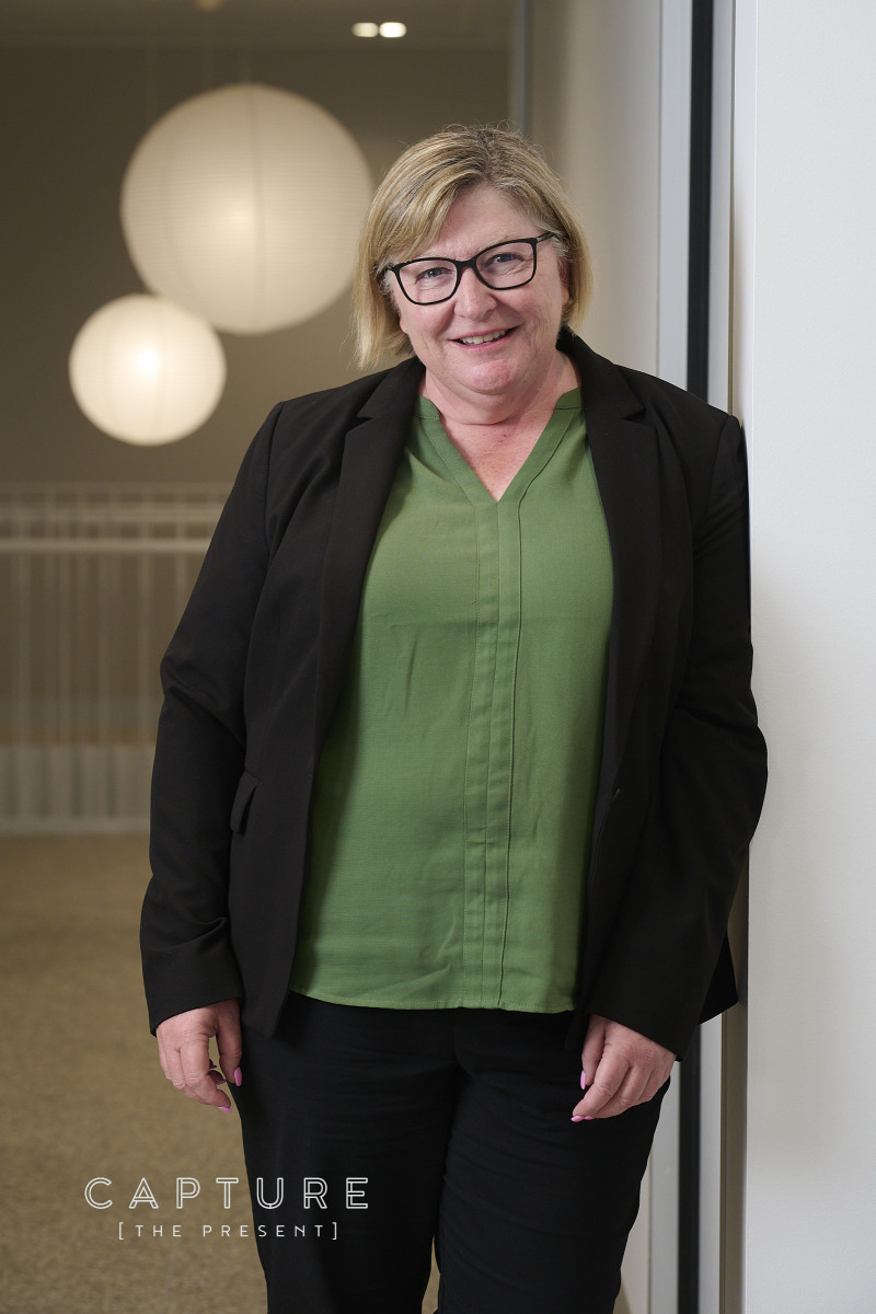 Staff member in a green top standing in a warmly lit office