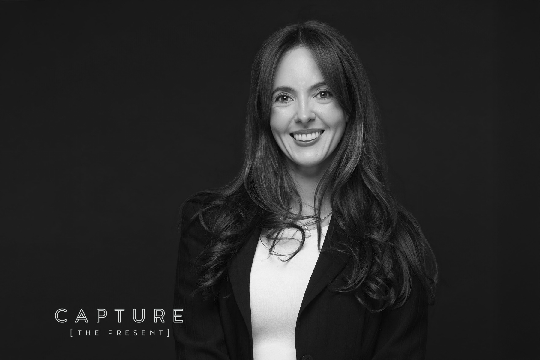 Woman with long dark hair photographed against a black backdrop