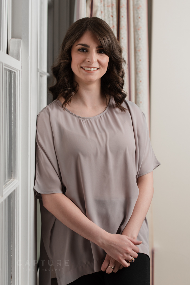 Professional standing by a window in a workplace portrait