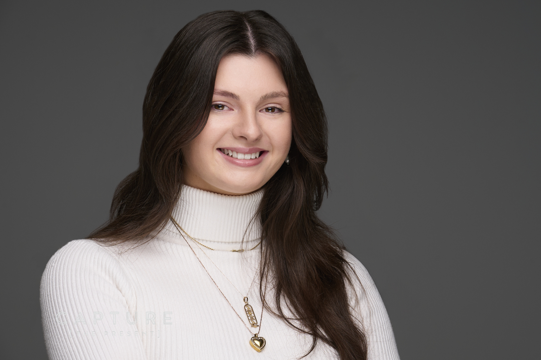 Woman with dark hair in a white top on a grey studio backdrop