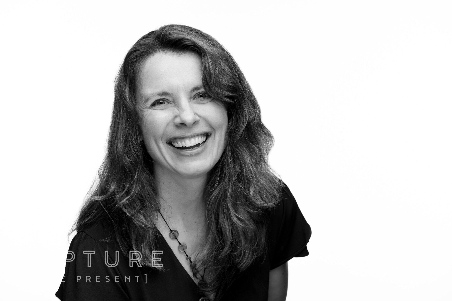 Black and white headshot of a smiling woman with dark curly hair