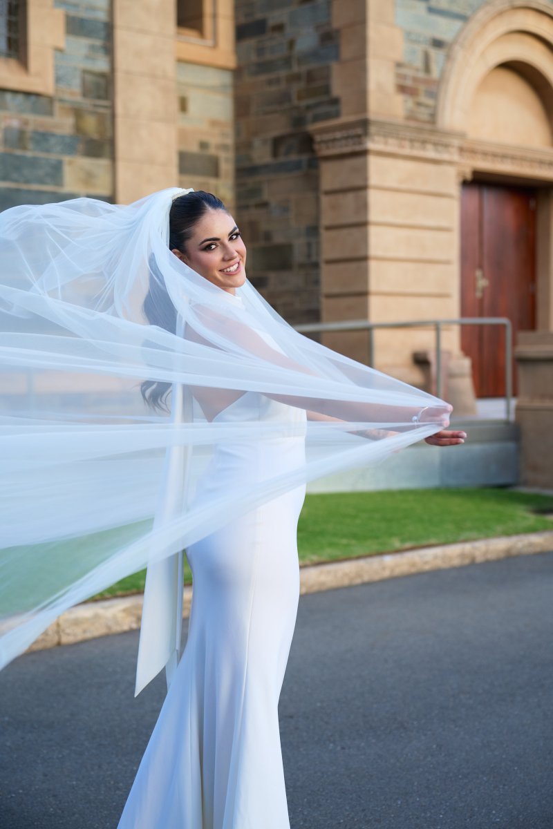 Stevie Hearl in the Sophia gown with a long blue veil at Sacred Heart College