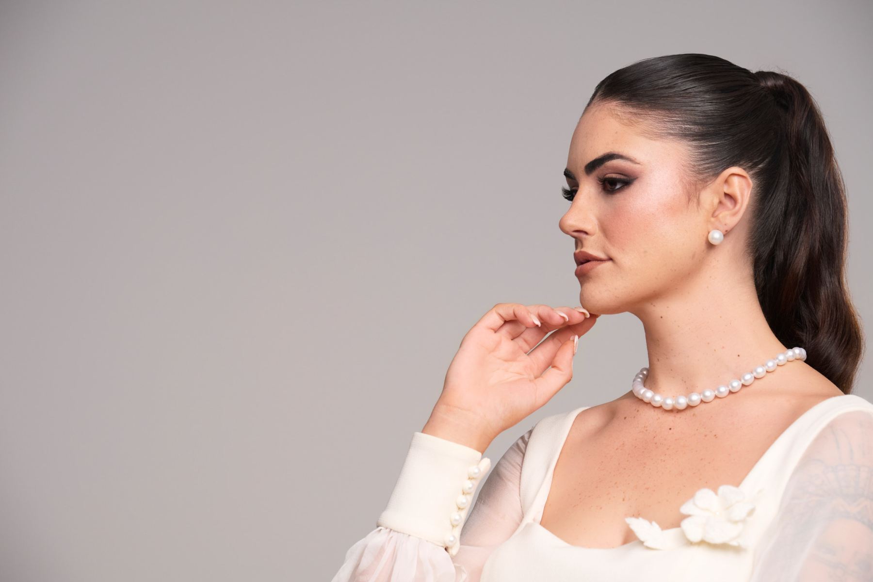 Stevie Hearl in close profile wearing the Chanel dress with pearls and sheer sleeve