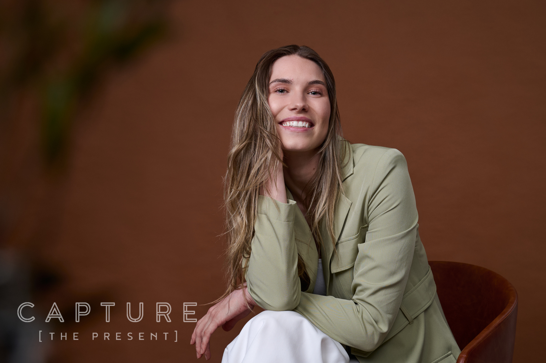 Caitlin Bahr in a sage blazer seated against a Gravity backdrop at Cog Creative Space