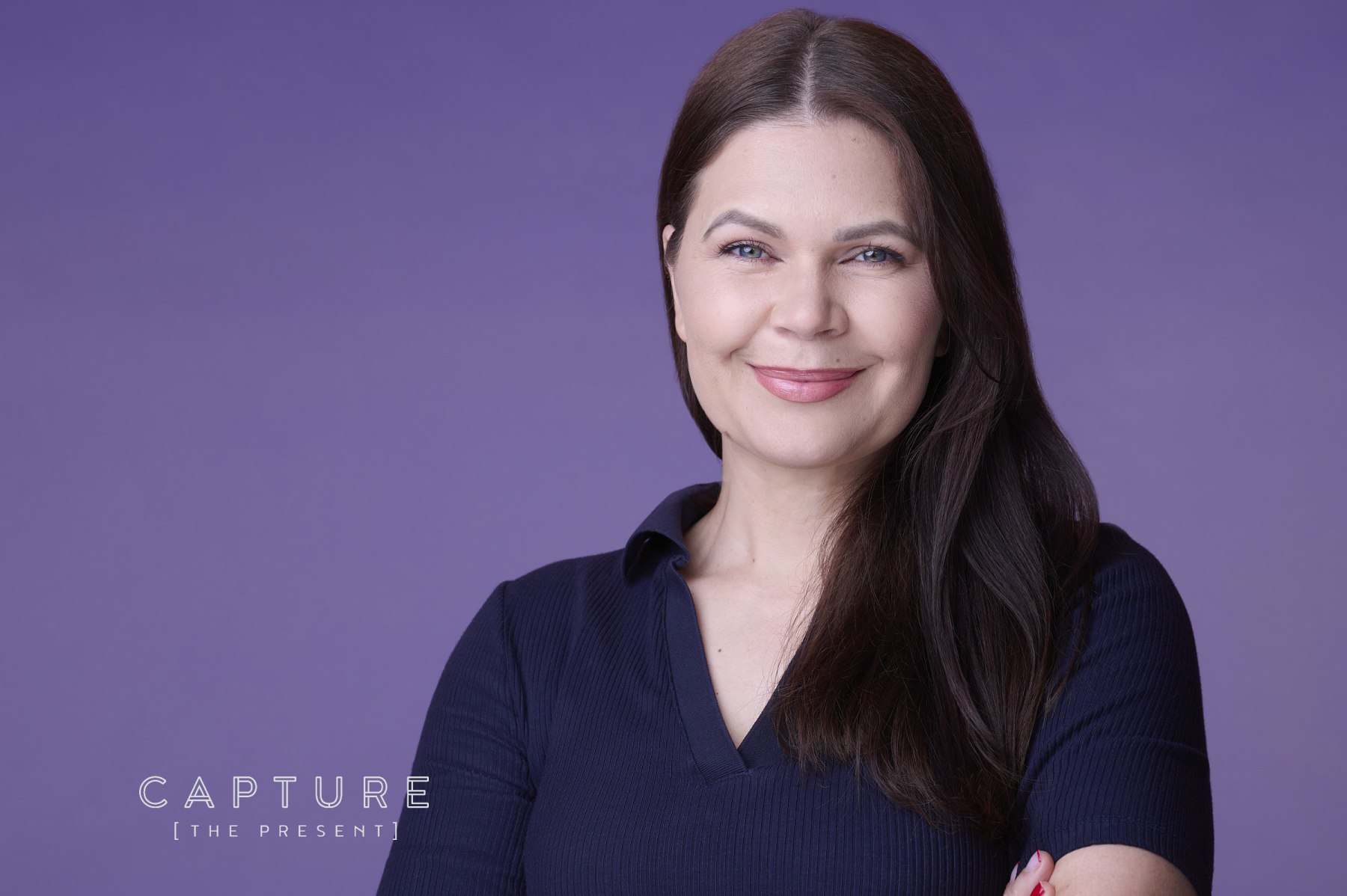 Woman with dark hair photographed against a purple backdrop