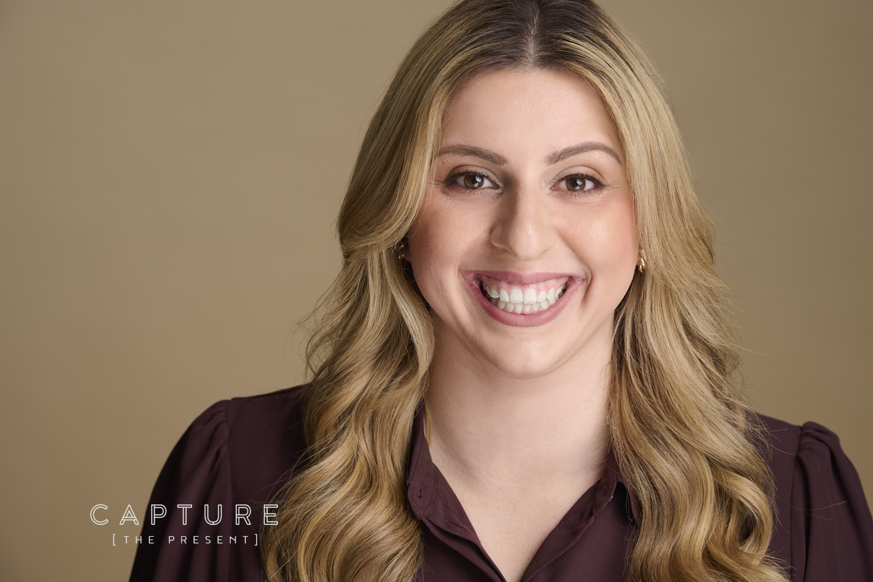 Smiling woman with long blonde hair on a warm-toned backdrop