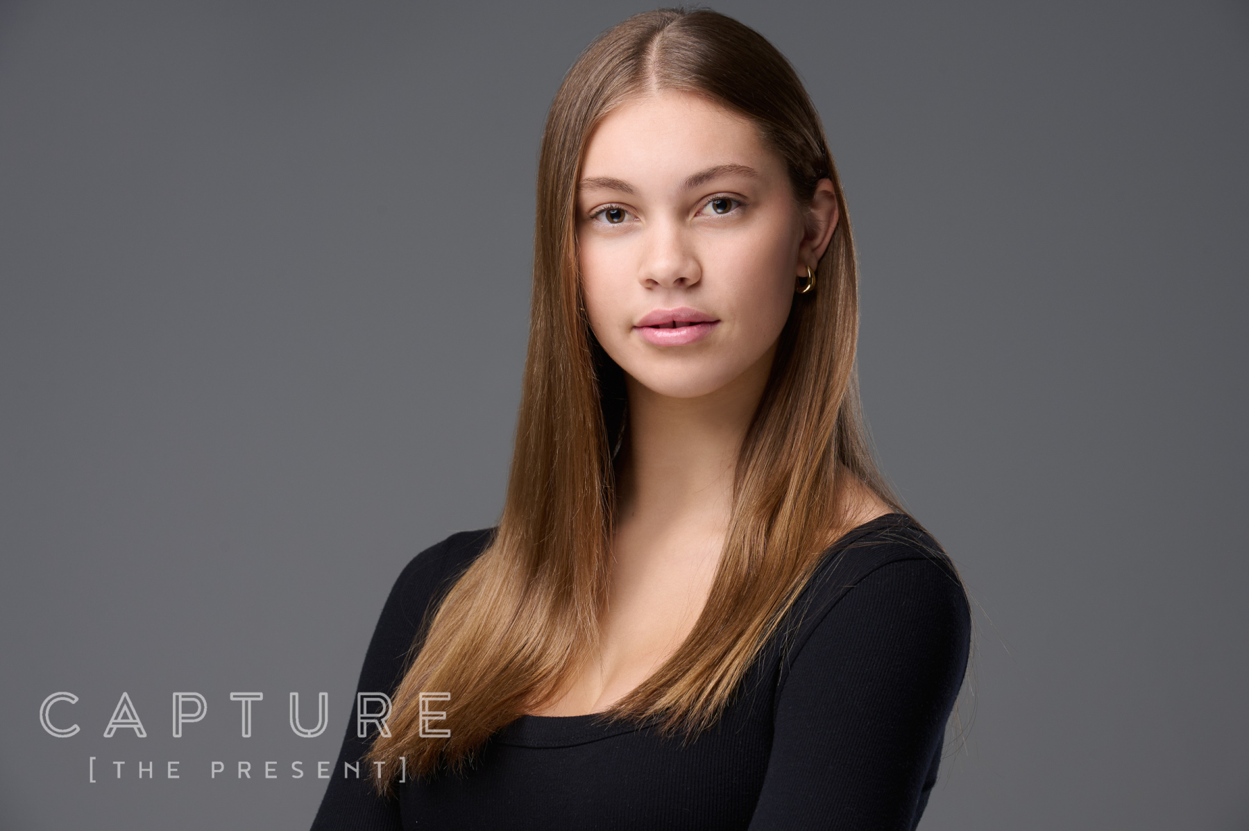 Young professional with long hair photographed on a charcoal backdrop