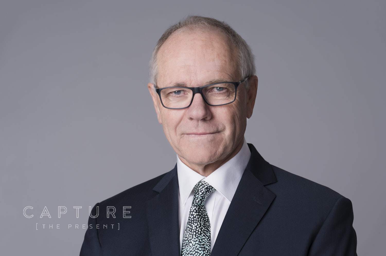 Senior lawyer in glasses and a suit on a grey backdrop