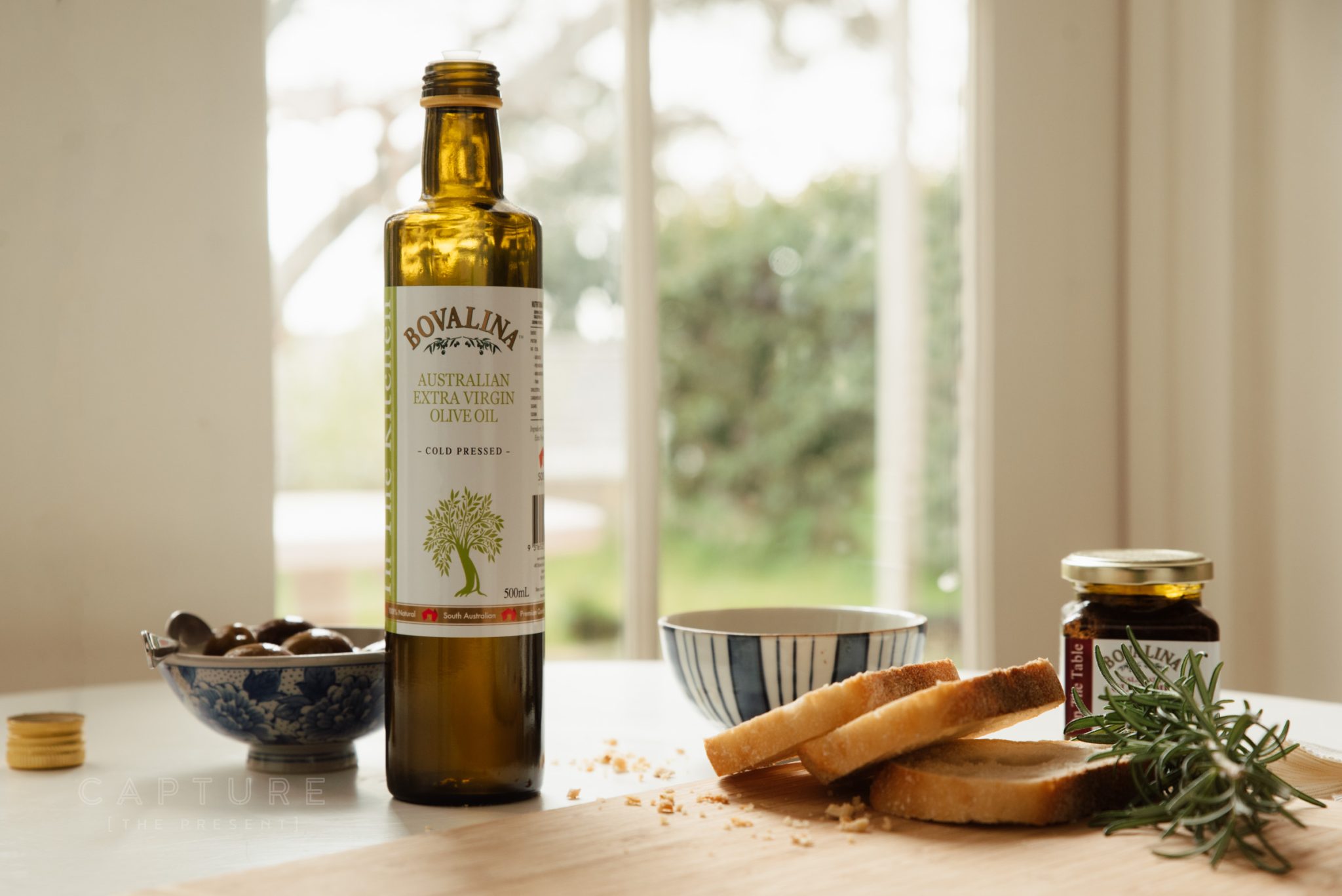 Bovalina olive oil bottle and preserves arranged on a table in soft daylight