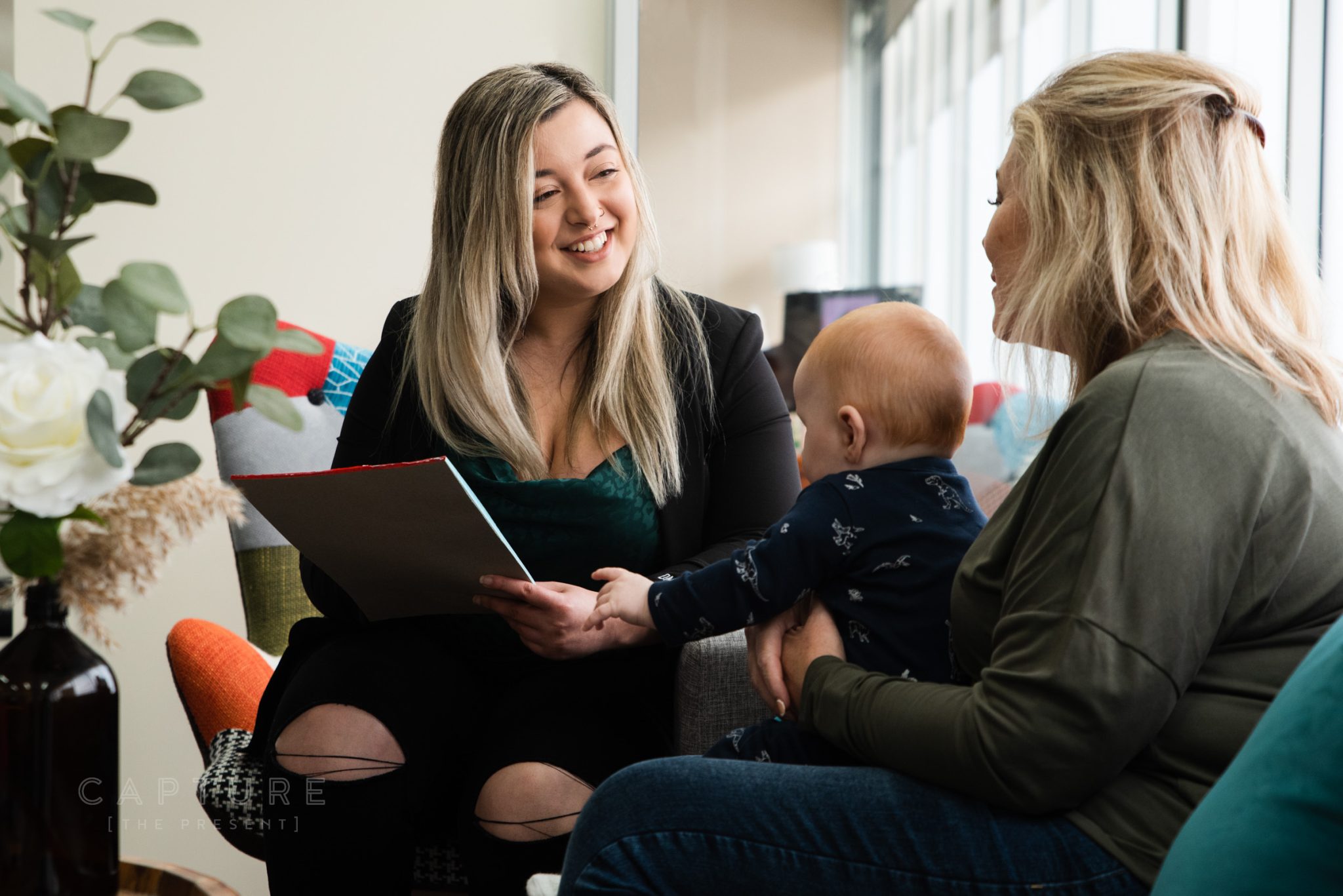 DMC Tax accountant Nicole going through paperwork on a laptop with a client and her baby