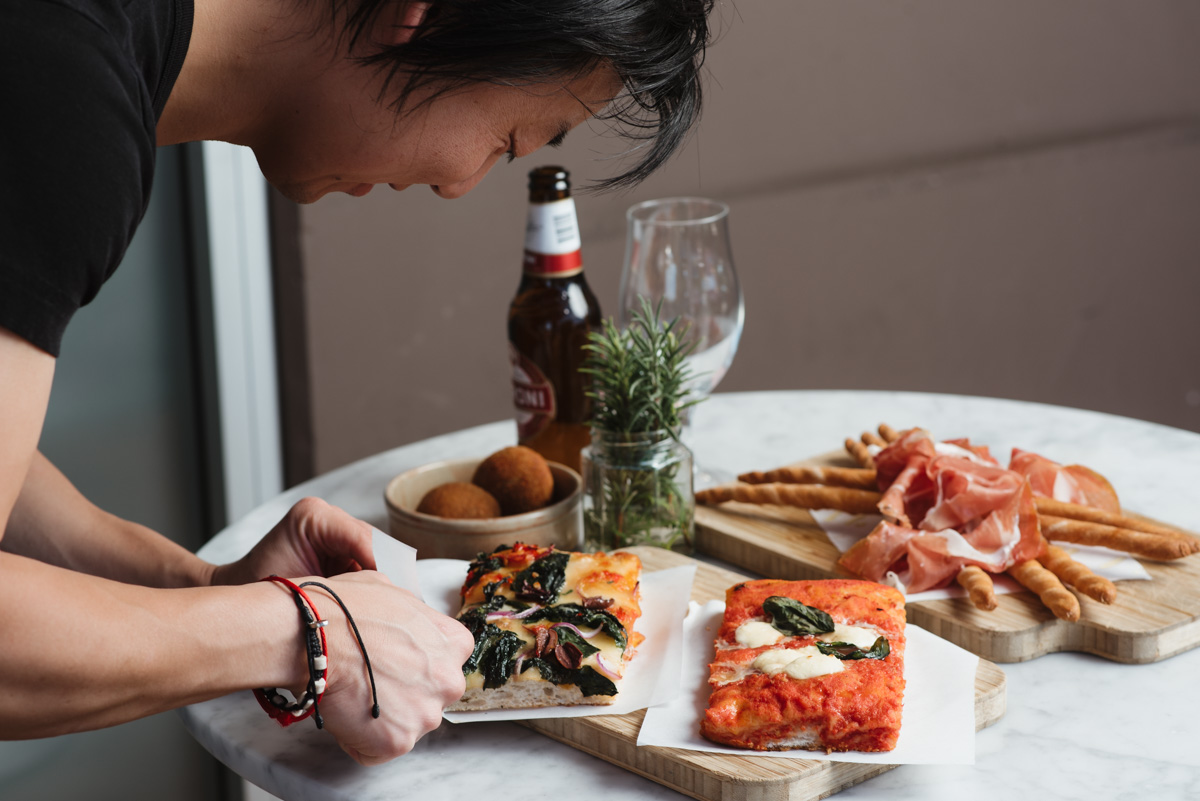 Stylist arranging pizza slices and charcuterie during a commercial food photoshoot