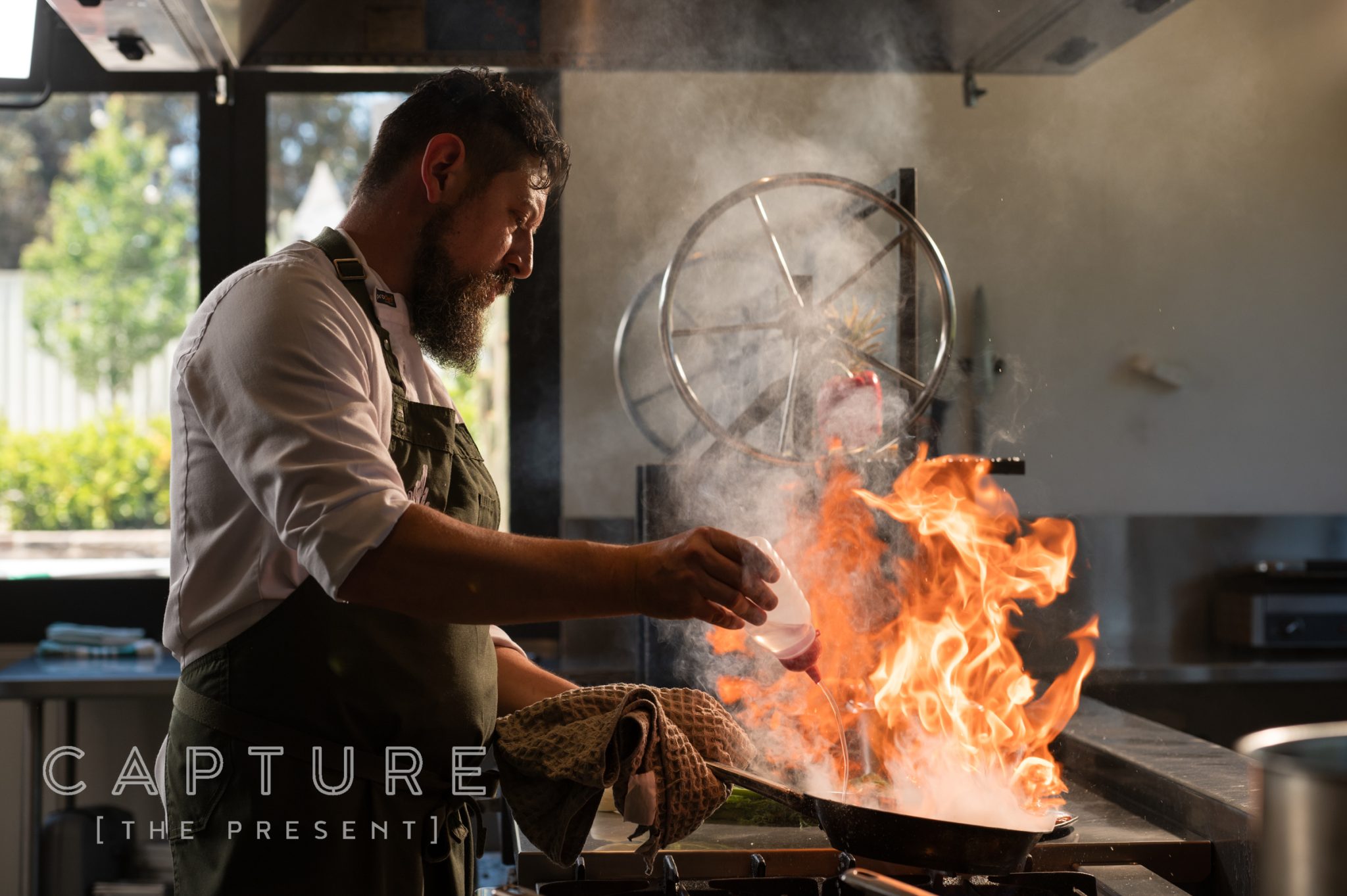 Chef flaming a pan in an open Barossa Valley restaurant kitchen El Estanco