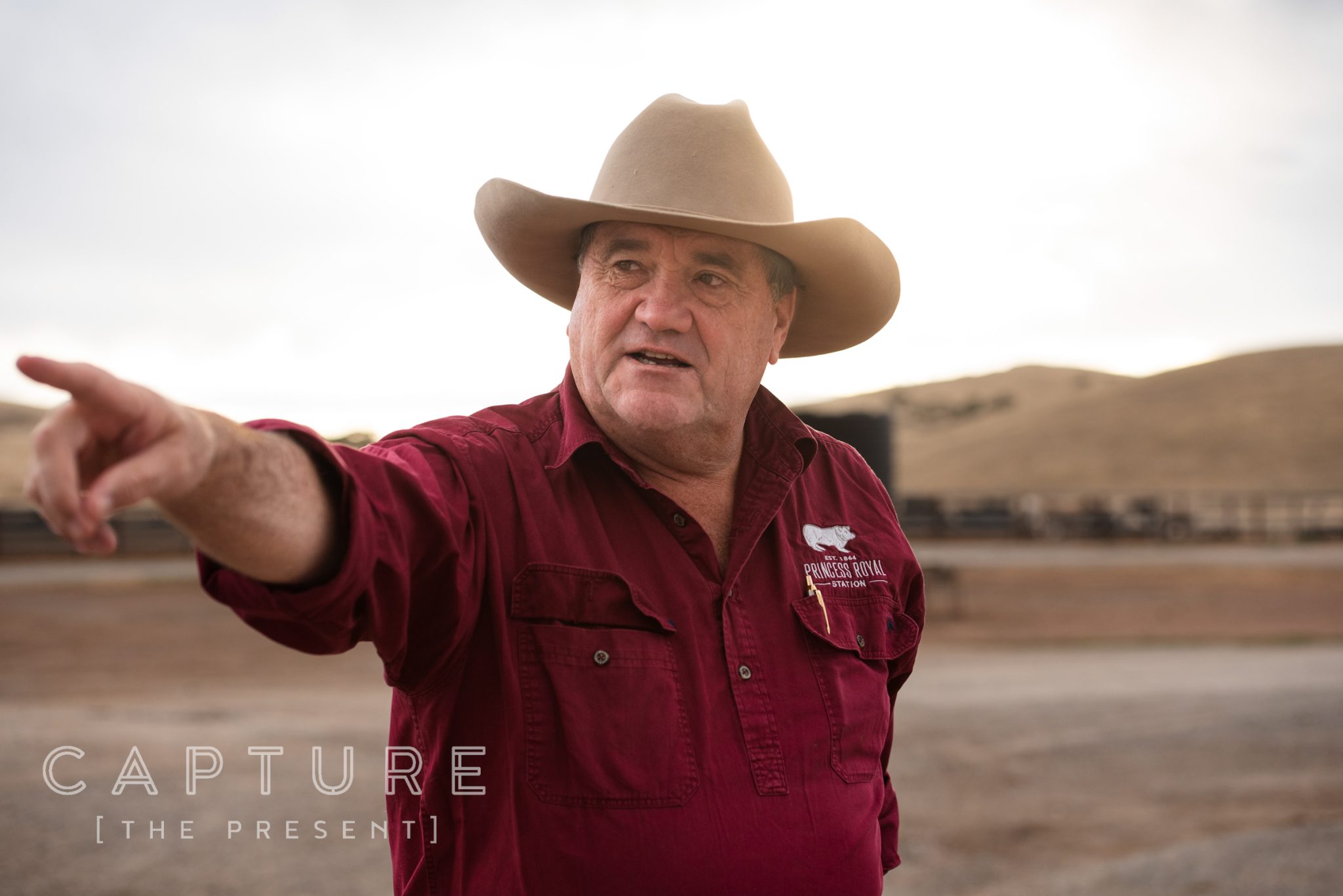 Owner of Princess Royal Station in a station shirt, pointing across the feedlot