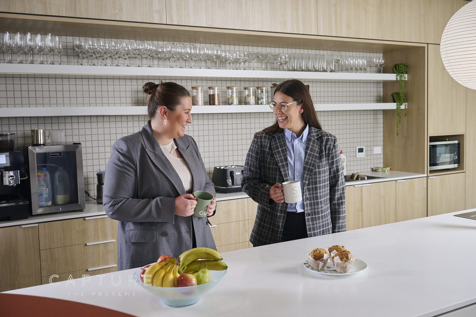Two Brentnalls colleagues laughing over coffee in their Adelaide office kitchen