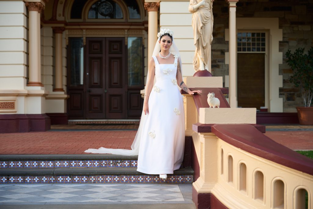 Stevie Hearl in the Grace gown and floral veil at the Sacred Heart College doors